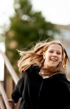 A teenage girl has fun and slides down the railing at the stadium.の写真素材
