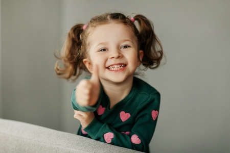 Portrait of a charming little girl with two ponytails, joyful and smilingの写真素材