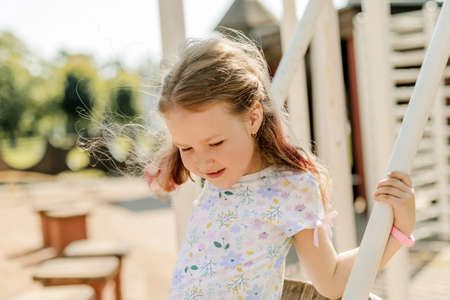 A charming girl is having fun on a swing on a summer day. Childhood, recreation, summer timeの写真素材