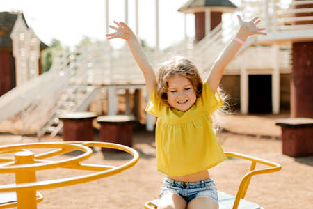 A charming little girl is walking in the park, swinging on a swing. Happy childhood, playtimeの写真素材