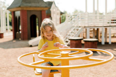 A charming little girl is walking in the park, swinging on a swing. Happy childhood, playtimeの写真素材