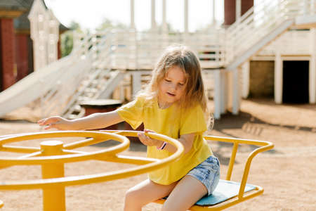 A charming little girl is walking in the park, swinging on a swing. Happy childhood, playtimeの写真素材