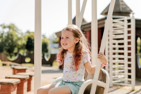 A charming girl is having fun on a swing on a summer day. Childhood, recreation, summer timeの写真素材