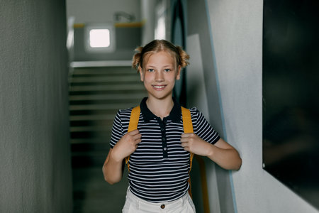A cheerful teenage girl with a backpack and a folder hurries to school. back to school, the concept of learning and educationの写真素材