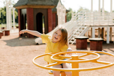 A charming little girl is walking in the park, swinging on a swing. Happy childhood, playtimeの写真素材