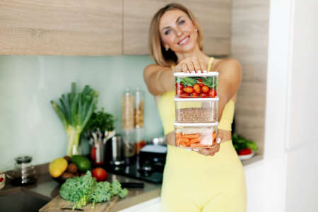 Containers with vegetables and buckwheat in the hands of a young woman. The concept of healthy eating and healthy lifestyle.の写真素材