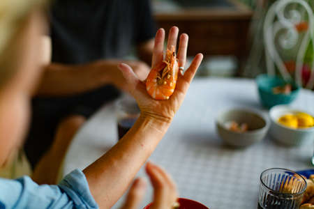 cooked shrimp on human hand by the served tableの写真素材