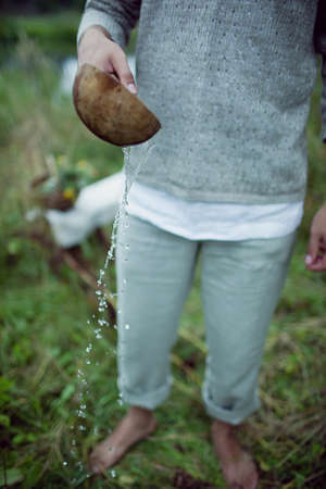 Man pouring water from a pot in the forest. Selective focus.