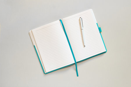 Open notebook with lined blank pages and pen on light gray background. Copy space, top view.の写真素材