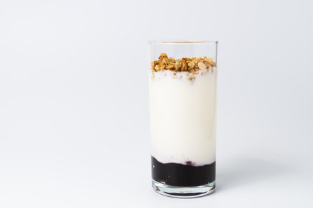 Healthy layered dessert with bio yogurt, granola and balckcurrant jam on white background.の写真素材