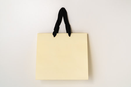 Mock up of beige paper shopping bag with black handles on white background.の写真素材