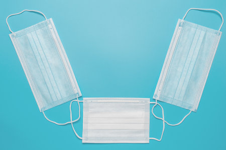 Medical protective masks on blue background. Disposable face masks for adults and children. Healthcare and protection against viruses for whole family.の写真素材