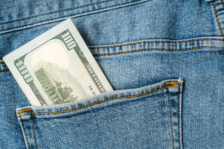 Stack of hundred dollar bills in the jeans pocket.