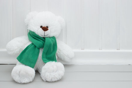 Child's toy white teddy bear with green scarf.の写真素材