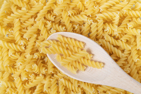 Raw or dry fusilli type of pasta with wooden spoon.の写真素材
