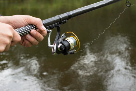 Fishing gear. Reel on a fishing rod against the background of the river.