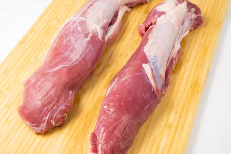 Raw pork tenderloin on a cutting board on white background. Fresh and juicy pork meat without fat.の写真素材