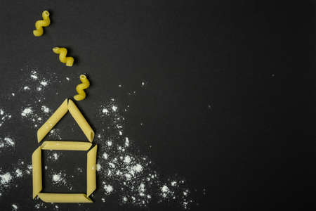 Picture with house made from italian pasta on black background.の写真素材