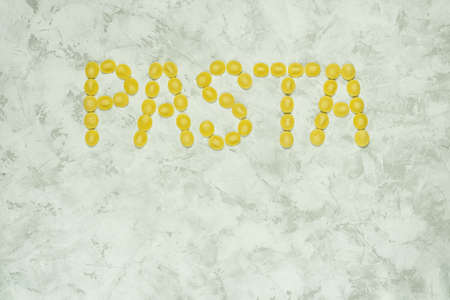 Inscription of word Pasta made from raw orecchiette type of pasta on gray background with space for text.の写真素材