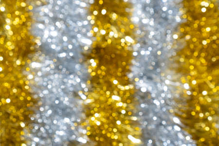 Blur golden and silver glittering tinsel. New Year or Christmas defocused abstract background.の写真素材