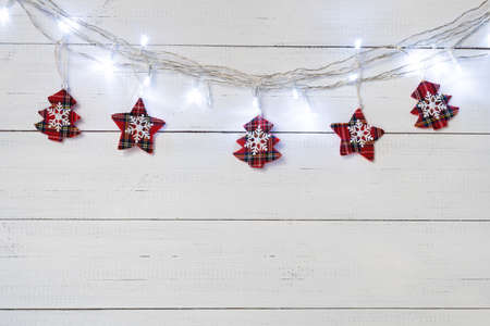Christmas background with garland lights and red textile baubles on white wooden boards.の写真素材