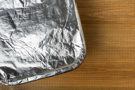 Tray with meal wrapped in aluminum foil for baking in the oven. Aluminum foil texture close up.の写真素材