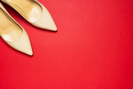 Classic beige patent leather court shoes noses on red background with copy space.の写真素材