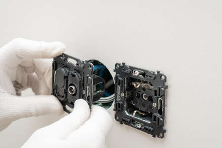 An electrician is installing multifunction outlet with internet connection, tv and electric socket ,...