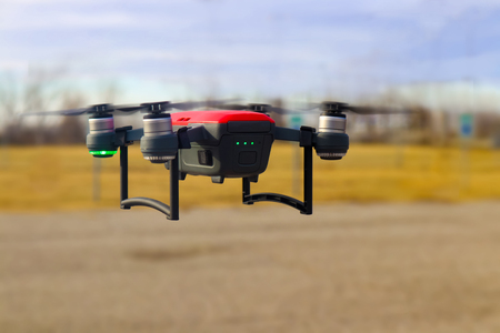 Small red and grey drone in flight  with three fourths battery charge against blurred background - winterの写真素材