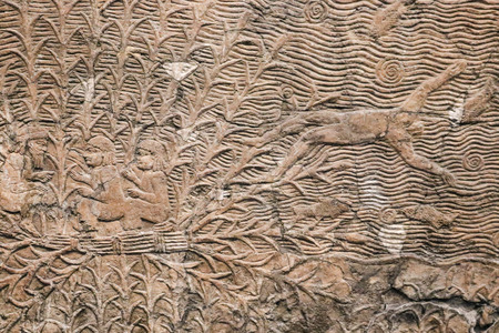 Ancient Egyptian stone panel with relief carving of man being thrown out of a boat into the ocean with fishes - Backgroundの写真素材