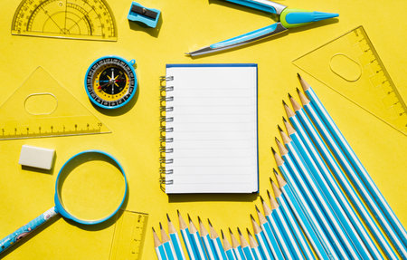 Spiral notepad with school supplies on yellow background. Creative education and office workspace flat lay.の写真素材