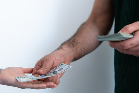 Male hands exchanging US dollars, illustrating a transaction.