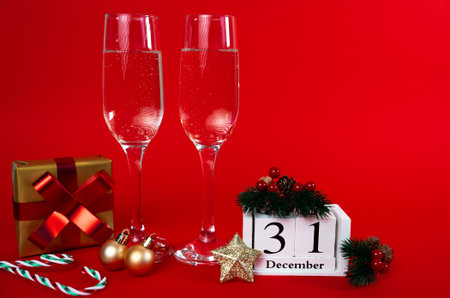 Two champagne glasses with gifts, ornaments and calendar showing 31 December. New Years Eve...