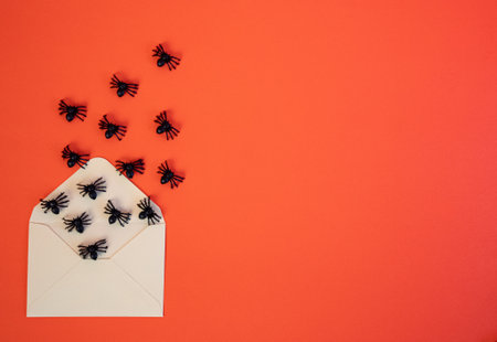 Spooky flat lay with spiders and house-shaped blank paper on orange backdrop. Perfect for Halloween design and seasonal concepts.の写真素材