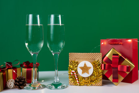 Holiday celebration scene with champagne glasses and red gift box on green background, symbolizing festive cheer.の写真素材