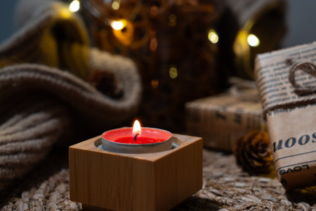 Close-up red tealight on a rustic surface with blurred fairy lights and fall textures. Perfect for seasonal marketing and blogs.の写真素材
