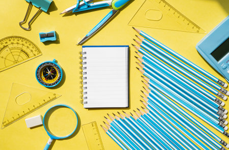Blank spiral notebook with education supplies on yellow background. Creative flat lay for study, learning, school preparation and design projects.の写真素材