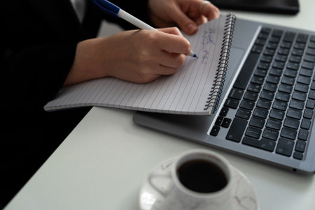 One hand on the keyboard, the other writing in a notebook. Clear message of multitasking, planning and time-management.の写真素材