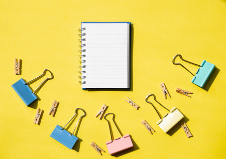 School and office supplies with notepad on yellow desk. Creative education and workspace flat lay for learning and study concepts.の写真素材
