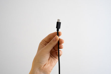 Hand showing USB cable on white surface. Perfect for technology, connection, charging, gadgets and digital communication concepts.の写真素材