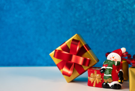 Holiday present with ribbon and Santa figurine on blue background. Ideal for Christmas cards and festive designs.の写真素材