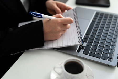 Tight crop of writing next to a laptop and cup. Suits content planning, study, copywriting, and productivity content.の写真素材