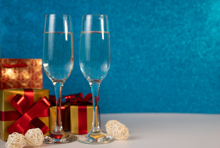 Elegant champagne flutes with wrapped golden gift on blue backdrop, premium New Year and holiday concept for celebrations and promotions.の写真素材