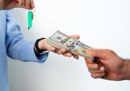 Male hand passing dollar bills to another person, symbolizing trade, debt repayment, or financial deal.の写真素材