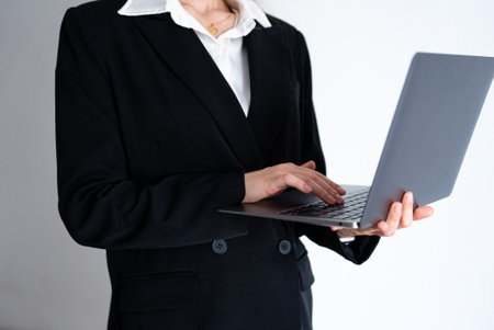 Woman in formal black suit holding laptop. Business, technology, corporate and remote work concept.の写真素材