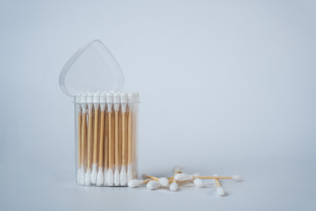 Transparent glass jar filled with white cotton swabs on a clean white background. Minimalistic home decor or hygiene concept in soft natural light.の写真素材