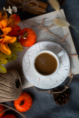 Vertical top view of a steaming cup amid autumn decor, small pumpkins, leaves and textured fabric create a cozy seasonal coffee moment.の写真素材