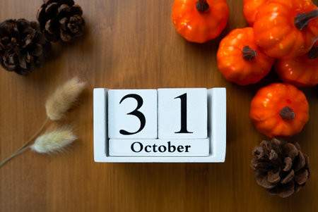 Top-down flat lay of wooden calendar blocks reading 31 October surrounded by mini pumpkins, pine cones and autumn props. Seasonal decor concept.の写真素材