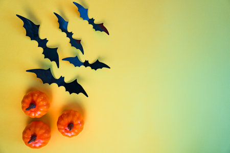 Pumpkins and bats on gradient yellow-green wall. Autumn Halloween background for greeting cards, invitations and festive promotions.の写真素材
