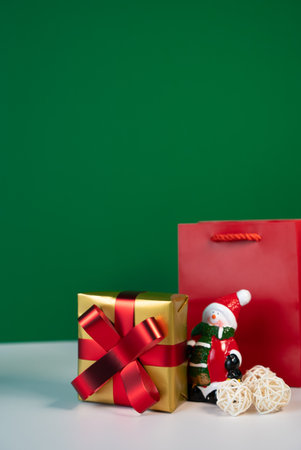 Small wrapped gift and holiday ornament on clean green backdrop, Minimal festive still life for seasonal banners and product mockups.の写真素材